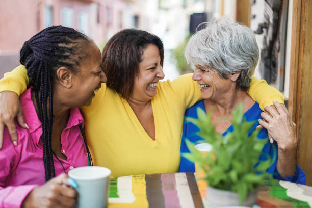 istock Multiracial senior friends having fun hugging at bar outdoor while drinking coffee together 1354406047