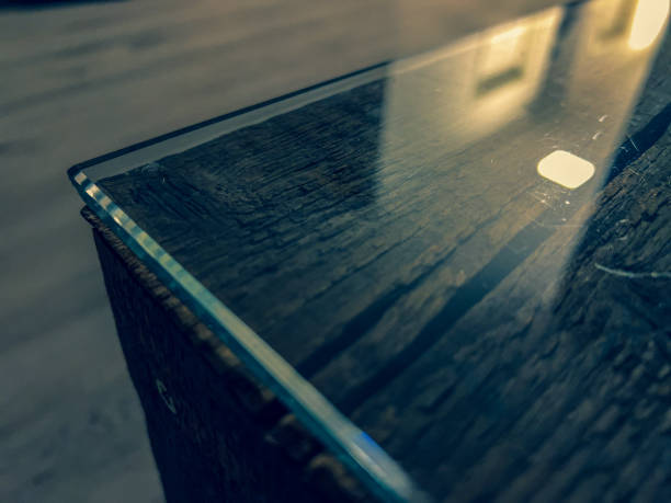 A table edge of a wooden table with glass top.