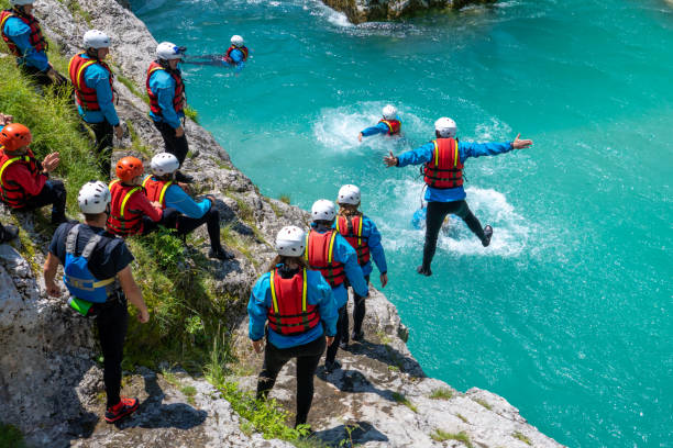 People enjoying sunny day with adrenaline activity in mountain gorge People enjoying sunny day with adrenaline activity in mountain gorge. Jumping into cold water from rock. Amazing turquoise clear water in Soca river, Slovenia. primorska white sport nature stock pictures, royalty-free photos & images