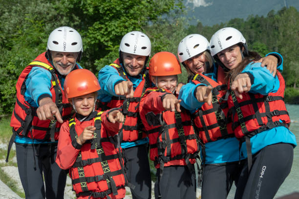 Family prepared for adventurous water experience posing at bank Family prepared for adventurous water experience posing at bank, looking and pointing at camera. Rafting in wild mountain Soca river, Slovenia. primorska white sport nature stock pictures, royalty-free photos & images