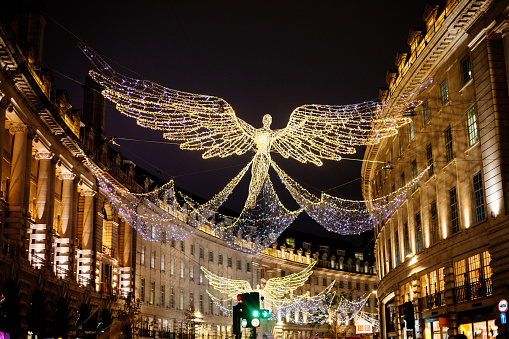 London, UK - November 2021: Regent Street with traffic at night and decorated annually with lights and angels for the Christmas season. This is a a main retail area of the capital