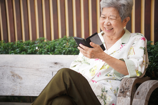 asian old asian elderly senior elder woman talking on smart mobile phone outdoor
