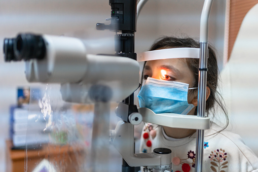 ophthalmologist is checking the eye vision of cute child in modern clinic