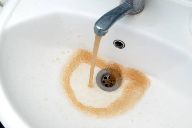 istock Dirty water from the tap. Rusty water flows into a white sink from a faucet. selective focus 1354419663