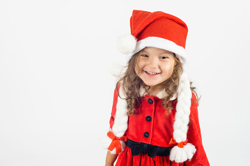 Little girl in santa costume with a toothy smile in front of white background