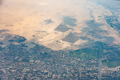 The Giza pyramid complex, also called the Giza Necropolis viewed from airplane window. Khufu, Khafre, Menkaure and Sphinx are visible.