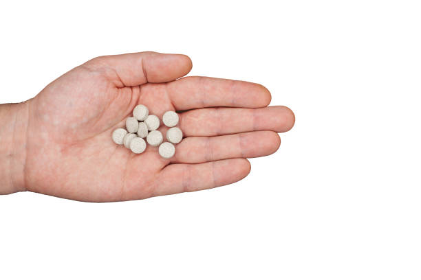 istock Male hand holding pills. Capsules are white. Medicines. Isolate 1354427845