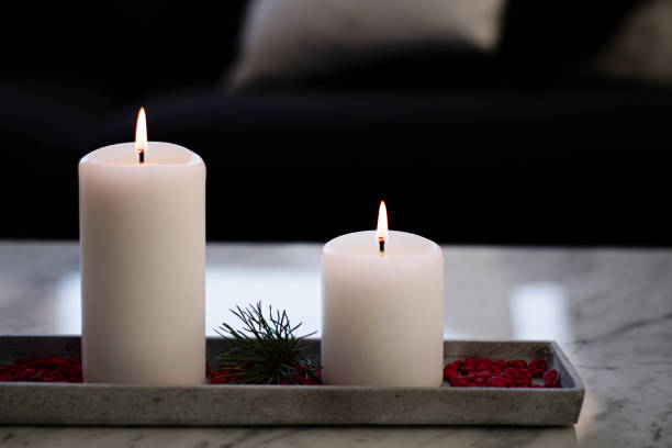 Two burning candles as winter and Christmas decoration indoors in the living room.