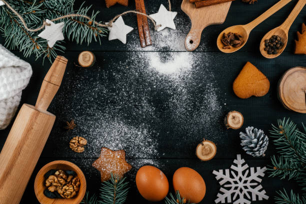 istock Christmas tree, gingerbread cookies, baking accessories and ingredients on black table with sprinkled flour. Copy space 1354433440