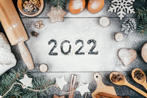 Numbers 2022 written on flour with branches of Christmas tree, baking accessories and ingredients. Happy New Year 2022 stock photo
