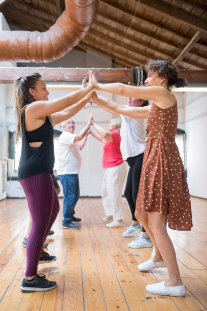 istock Cheerful young Caucasian instructor dancing in pairs with seniors 1354441763