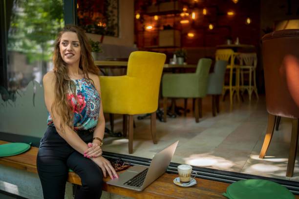 istock Businesswoman using laptop while enjoying work at cafe table with cup of coffee 1354443151