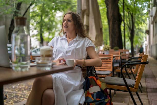 istock Businesswoman using laptop while enjoying work at cafe table with cup of coffee 1354443216