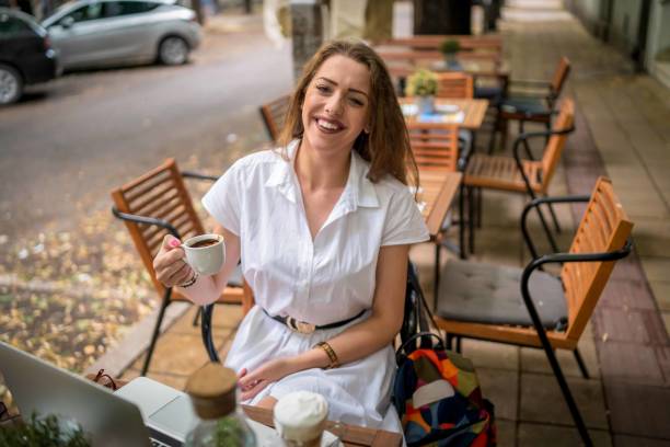 istock Businesswoman using laptop while enjoying work at cafe table with cup of coffee 1354443277
