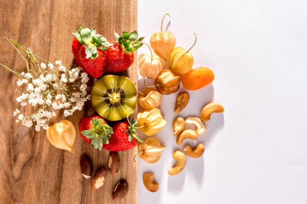 Kiwi, strawberries, cashews, Brazil nuts and physalis on wooden background, Top view