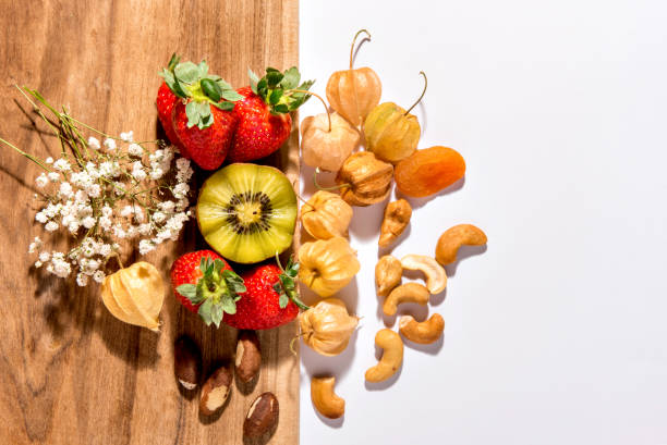 Kiwi, strawberries, cashews, Brazil nuts and physalis on wooden background. Top view.