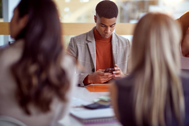 istock man on meeting looking at mobil phone 1354448273