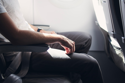 Man resting during flight. Legroom between seats in commercial airplane. 