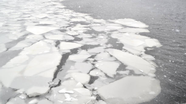 Cracked ice on a frozen river on a snowy winter day stock photo