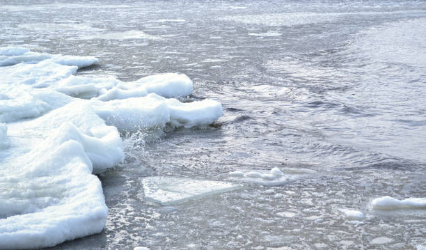 River splashing the frozen shore on a cold winter day stock photo