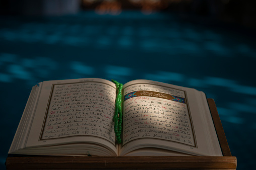 quran holy book of muslims, islam. Holy book quran illuminated by daylight inside a modern mosque. Quran - the holy book of Muslims in the mosque. Muslims glorify Allah (God). Old Korans and prayer beads standing on the stand of the Koran in the mosque