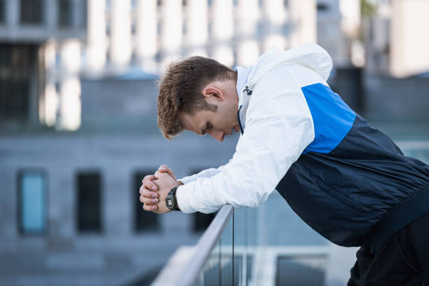 Young tired athlete resting after training outdoors Profile portrait of young tired athlete resting after hard training outdoor. Sportsman relaxing after workout exercise, breathing fresh air lean on fence in city. Sport and competition failure concept blocking sports activity stock pictures, royalty-free photos & images