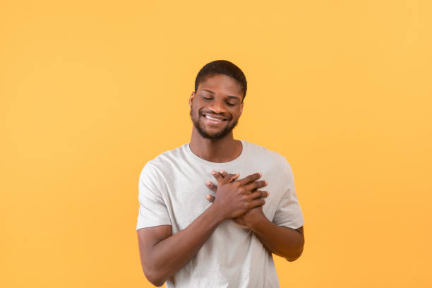istock Cordial black guy holding his hands on chest, expressing gratitude and positive emotions, yellow background 1354463543