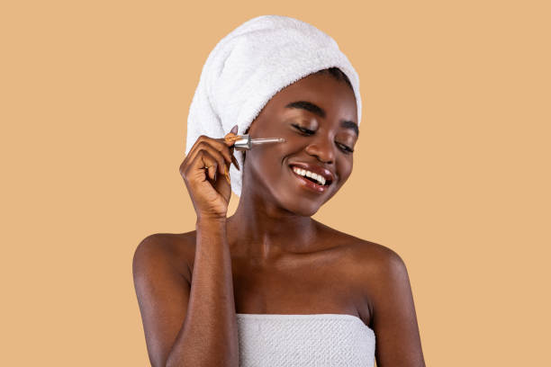 istock Portrait of smiling black woman using serum 1354463769