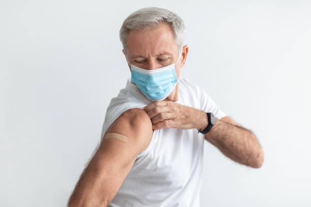 istock Vaccinated Older Man Wearing Mask Showing Arm After Vaccination, Studio 1354465354