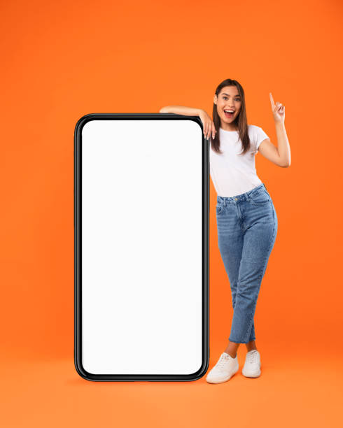istock Woman pointing up leaning on big white empty smartphone screen 1354465413
