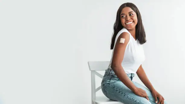Photo of Happy Vaccinated Woman With Adhesive Bandage On Shoulder Looking Away