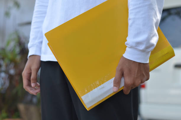 istock male hands bring yellow document in outdoor view 1354468303