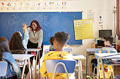 istock Teacher and Schoolgirl Exchanging High-Five in Classroom 1354472037