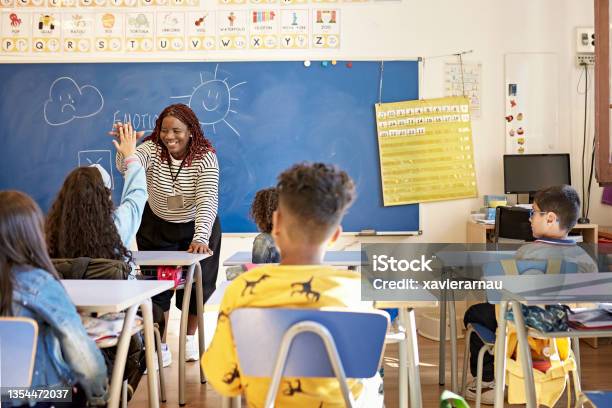 Teacher And Schoolgirl Exchanging Highfive In Classroom Stock Photo - Download Image Now