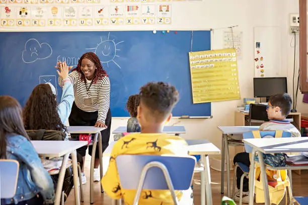 Photo of Teacher and Schoolgirl Exchanging High-Five in Classroom