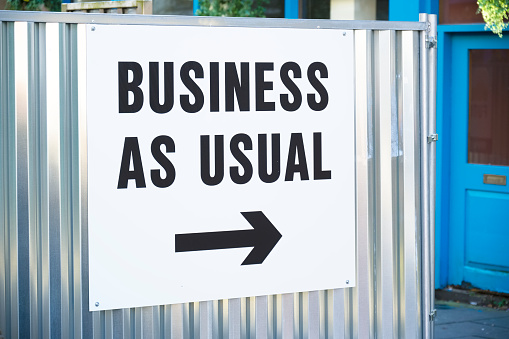 Business as usual open sign with direction arrow UK
