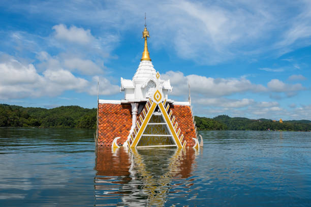 Ancient temple flooded by Songkalia river with blue sky in Sangkhlaburi, Karnchanaburi, Thailand. Touring boat sailing to visit from city. Famous travel destination in siam.
