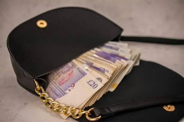 Photo of hand bag ,purse with  UK pounds banknotes background. Money of United Kingdom.