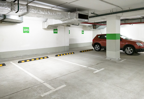 Underground car parking, empty modern parking lot indoor. Inside light parking garage in mall basement.