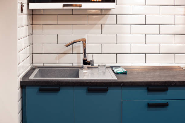 istock Kitchen design with white brick tiles and a dark countertop with a deep sink. Home modern interior 1354494630