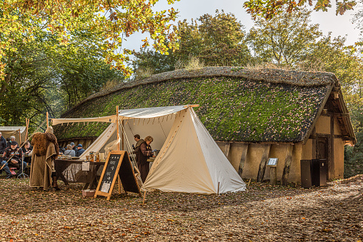 Tent at a Viking bazaar in front of a reconstruktion of a Viking longhouse in Frederikssund, Denmark, October 23, 2021