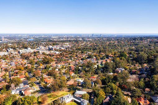 Elevated aerial view over endless residential suburbs of Greater Sydney towards Parramatta high-rise towers and Sydney West.