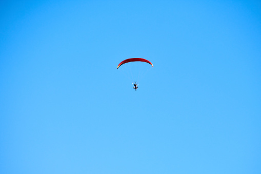 Powered parachute in clear blue sky, motorized parachute overhead view, extreme tourism copy space