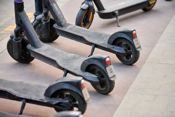 Photo of Motorized scooter parking for hourly rent on sidewalk street, vehicle for fast movement around town