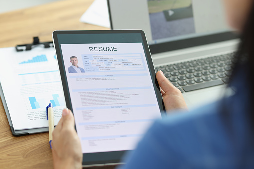 Woman employer holding digital tablet in hands with resume of man for employment closeup. Remote employment concept