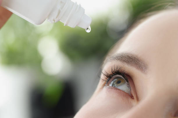 woman dripping moisturizing drops into her eye closeup - lubrication infection imagens e fotografias de stock