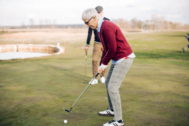 istock Mature woman taking a golf shot 1354515260