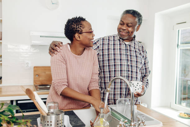 african american senior woman washing dishes and relaxing with her husband - senior getting groomed studio imagens e fotografias de stock