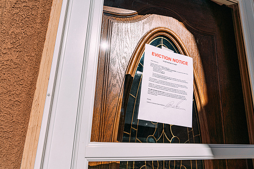 Toma de ángulo bajo de un aviso de desalojo de papel pegado a la puerta principal de vidrio de una casa de alquiler en un vecindario suburbano residencial photo