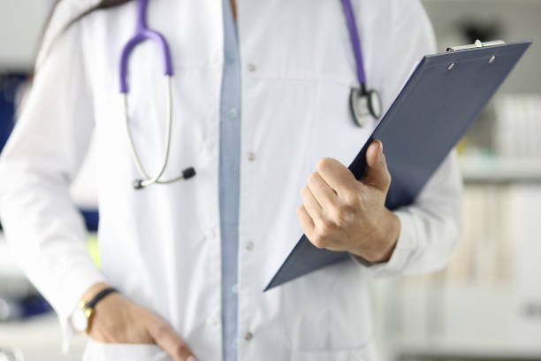 istock Doctor in white coat holding clipboard with documents in clinic 1354521749